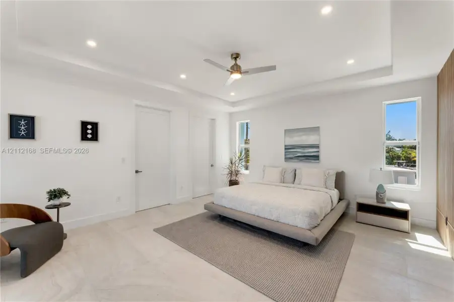 Tray ceiling featuring recessed lighting, a central ceiling fan, large-format tile flooring, and floor-to-ceiling wood-finish cabinetry Tray ceiling featuring recessed lighting, a central ceiling fan, large-format tile flooring, and floor-to-ceiling wood-finish cabinetry