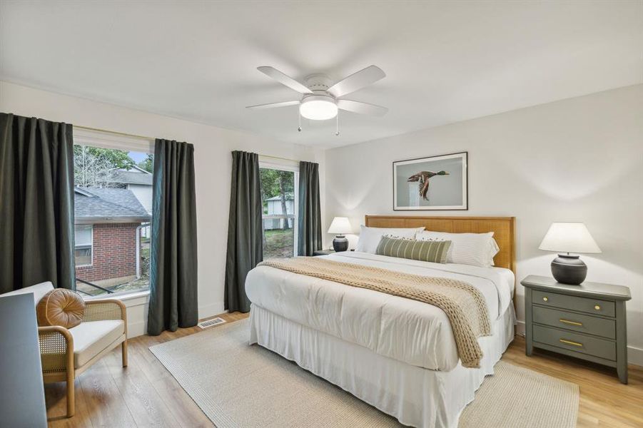 Bedroom featuring ceiling fan, multiple windows, and light hardwood / wood-style floors