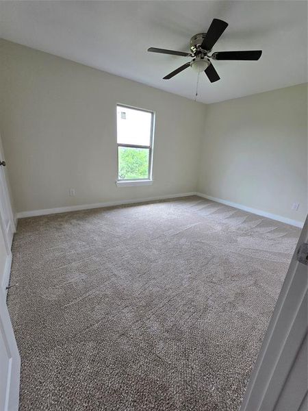 Carpeted spare room featuring a ceiling fan and baseboards