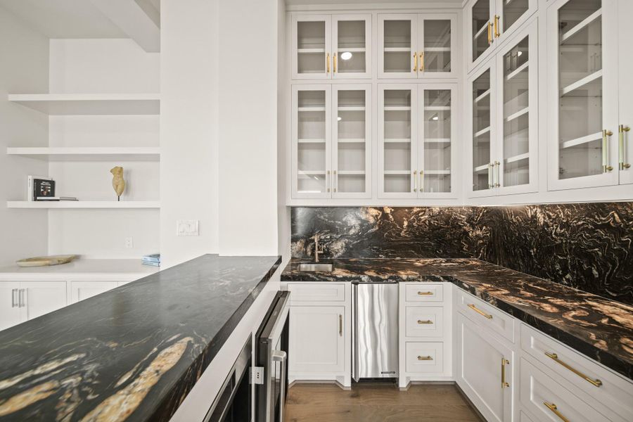 Wet bar found on the second floor, neighboring the living room. Complete with quartzite countertops, custom, built on site, cabinetry, Wolf coffee machine, ice machine, Wolf beverage cooler, and a temperature controlled wine room.
