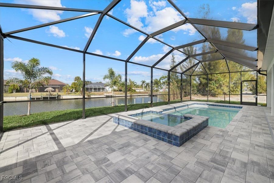 View of swimming pool with a water view, a sunroom, glass enclosure, a pool with connected hot tub, and a patio area