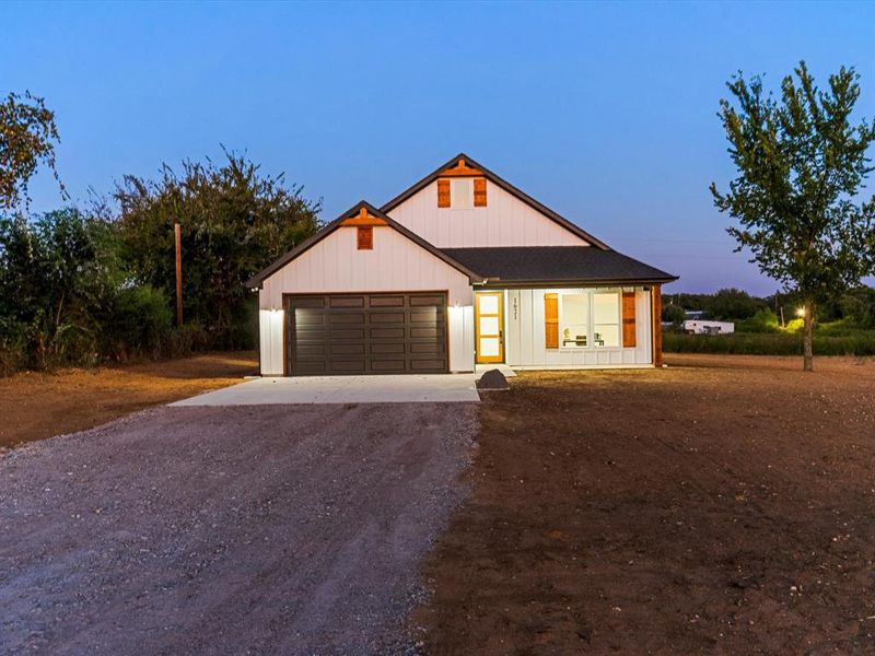 Modern farmhouse featuring dirt driveway, a garage, and board and batten siding