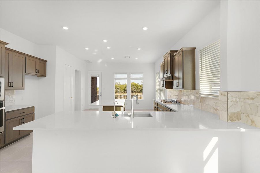 Kitchen with a sink, a peninsula, recessed lighting, light countertops, and appliances with stainless steel finishes