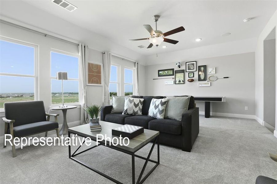 Spacious room featuring multiple windows, light gray carpet flooring, a ceiling fan with integrated lighting, and recessed ceiling lights Spacious room featuring multiple windows, light gray carpet flooring, a ceiling fan with integrated lighting, and recessed ceiling lights