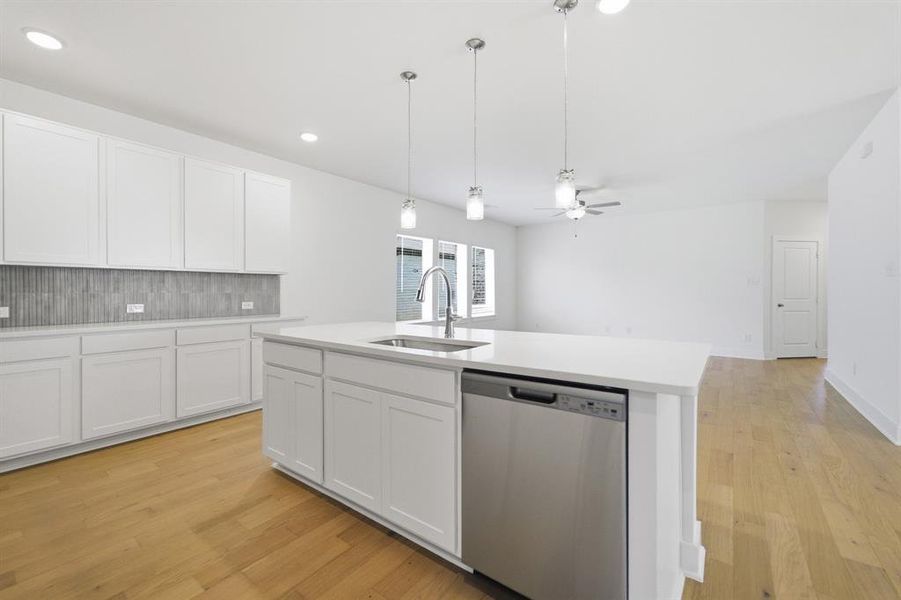 Kitchen island featuring an undermount sink, gooseneck faucet, and integrated dishwasher