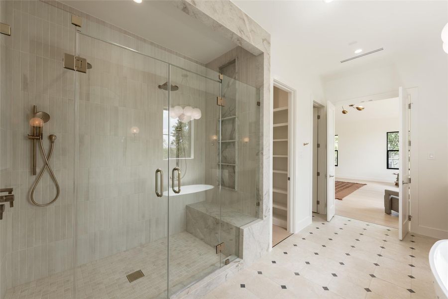 The oversized glass enclosed shower brings another layer of luxury to the primary bath, with full height designer tile and a built in bench creating a spa like experience at home. The oversized glass enclosed shower brings another layer of luxury to the primary bath, with full height designer tile and a built in bench creating a spa like experience at home.