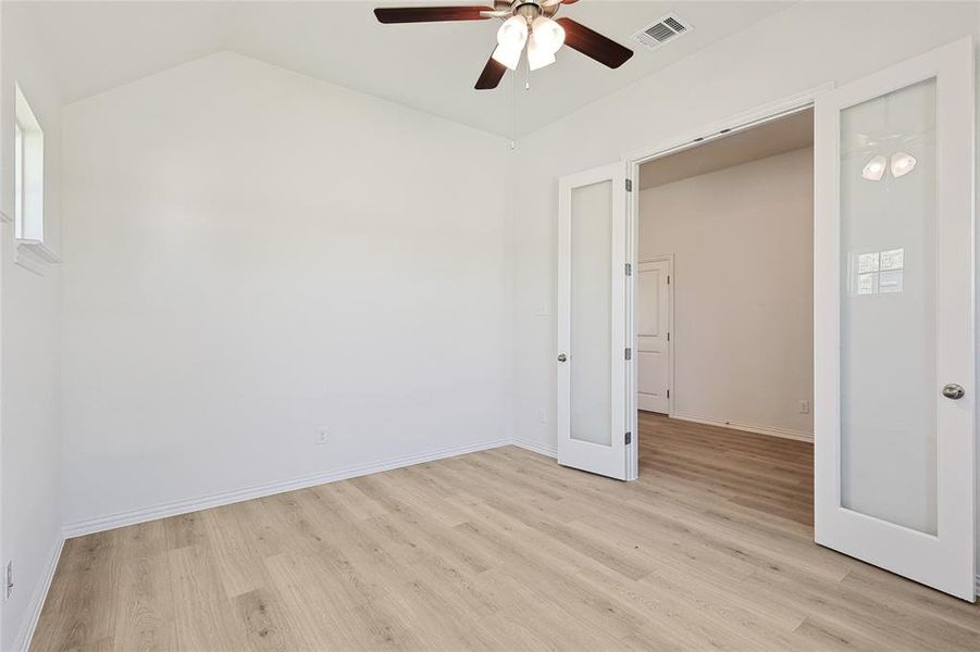 Spare room featuring lofted ceiling, ceiling fan, and light hardwood / wood-style floors