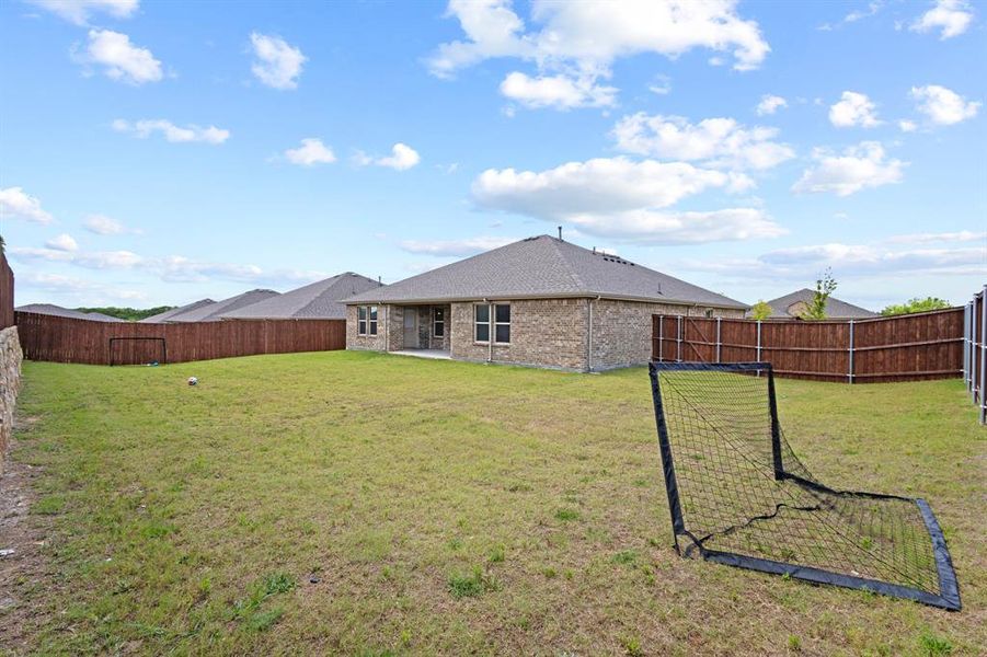 Expansive rear yard featuring a privacy fence, brick exterior, covered patio, and well-maintained lawn Expansive rear yard featuring a privacy fence, brick exterior, covered patio, and well-maintained lawn