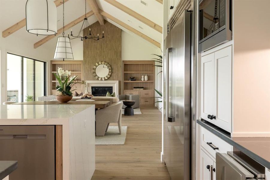 Kitchen featuring high vaulted ceiling, built in appliances, a fireplace, beam ceiling, and light wood-type flooring Kitchen featuring high vaulted ceiling, built in appliances, a fireplace, beam ceiling, and light wood-type flooring