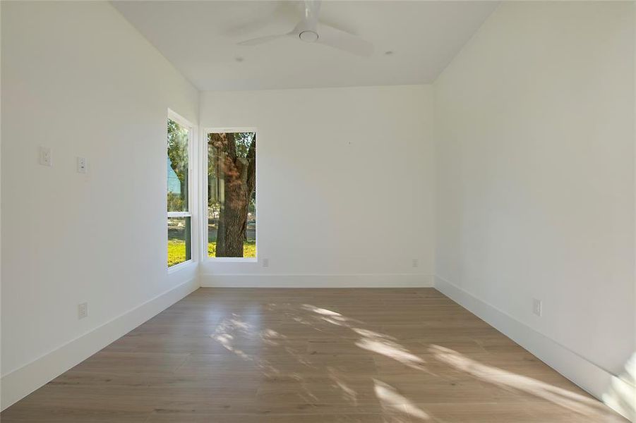 Empty room with hardwood / wood-style flooring, ceiling fan, and plenty of natural light