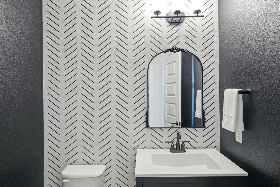 Bold patterned accent wall and modern fixtures create a striking and inviting powder room. Bold patterned accent wall and modern fixtures create a striking and inviting powder room.