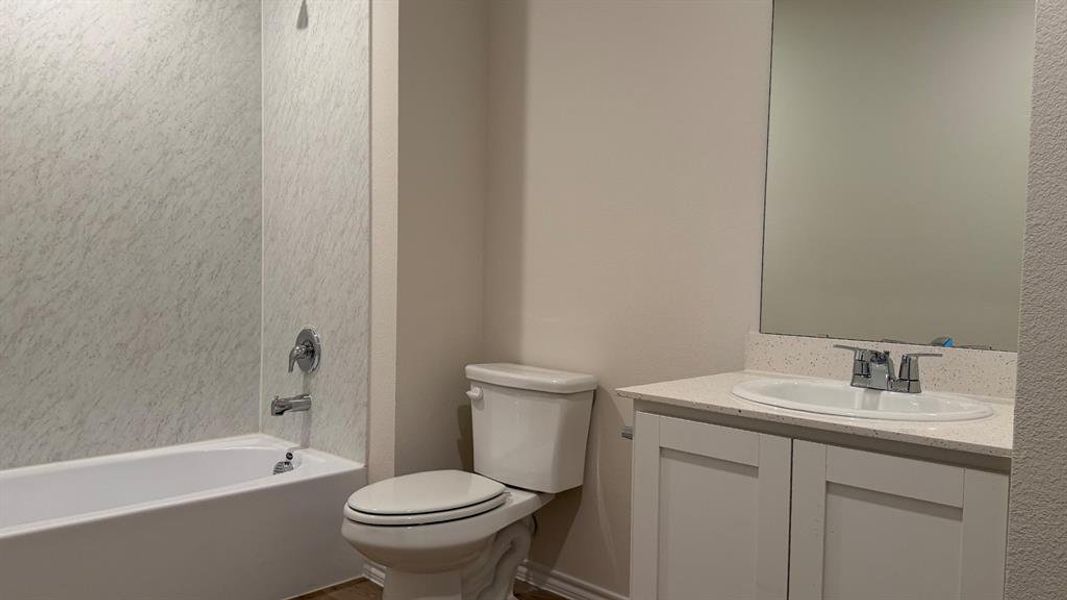 Full bathroom featuring a white porcelain tub with integrated shower, chrome fixtures, and a textured wall surround