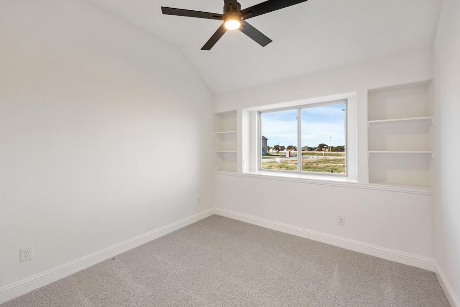 Empty bedroom with carpet, ceiling fan, built-in shelves flanking a large window with neighborhood view Empty bedroom with carpet, ceiling fan, built-in shelves flanking a large window with neighborhood view