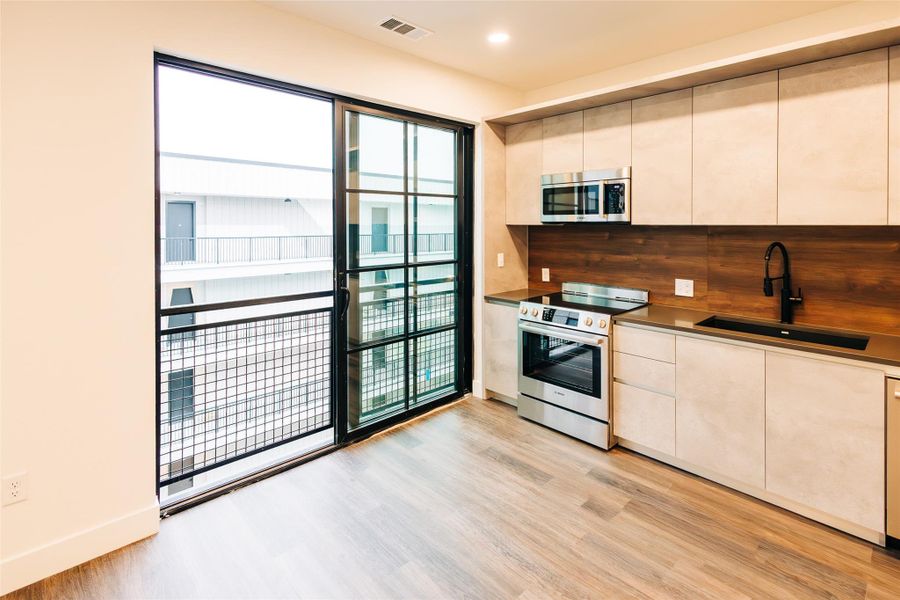 Kitchen featuring appliances with stainless steel finishes, light wood-type flooring, modern cabinets, recessed lighting, and tasteful backsplash