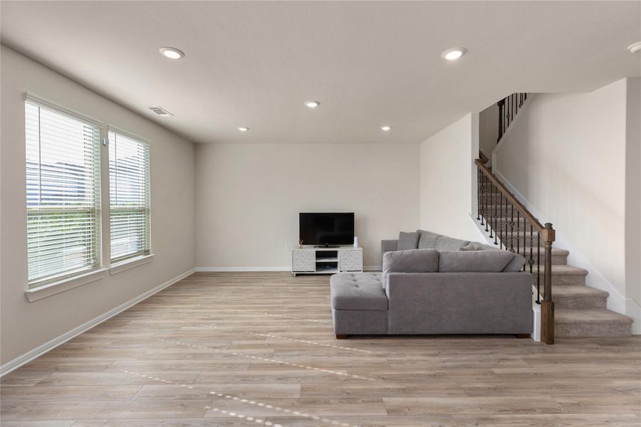 Living area with recessed lighting, light wood-style floors, and stairway