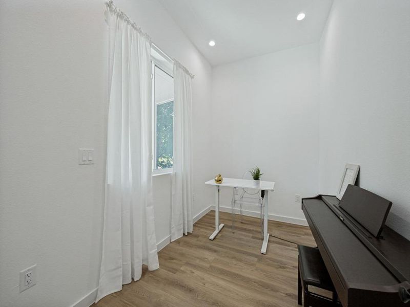 Well-lit room with recessed lighting and warm wood flooring offers a versatile space for work or leisure. Well-lit room with recessed lighting and warm wood flooring offers a versatile space for work or leisure.