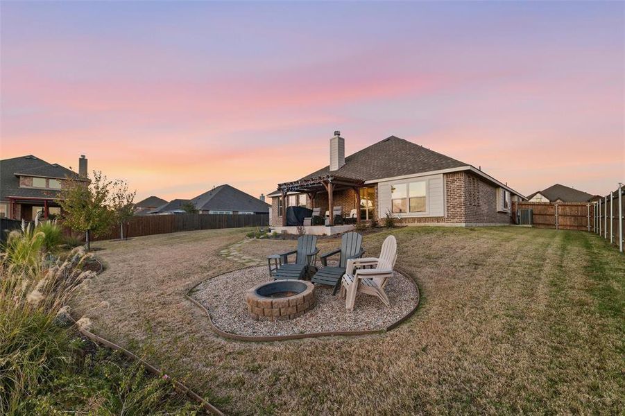 Back of home with stone path leading from the pergola down to the gas fire pit. Beautiful landscaping borders the rot iron fence Back of home with stone path leading from the pergola down to the gas fire pit. Beautiful landscaping borders the rot iron fence