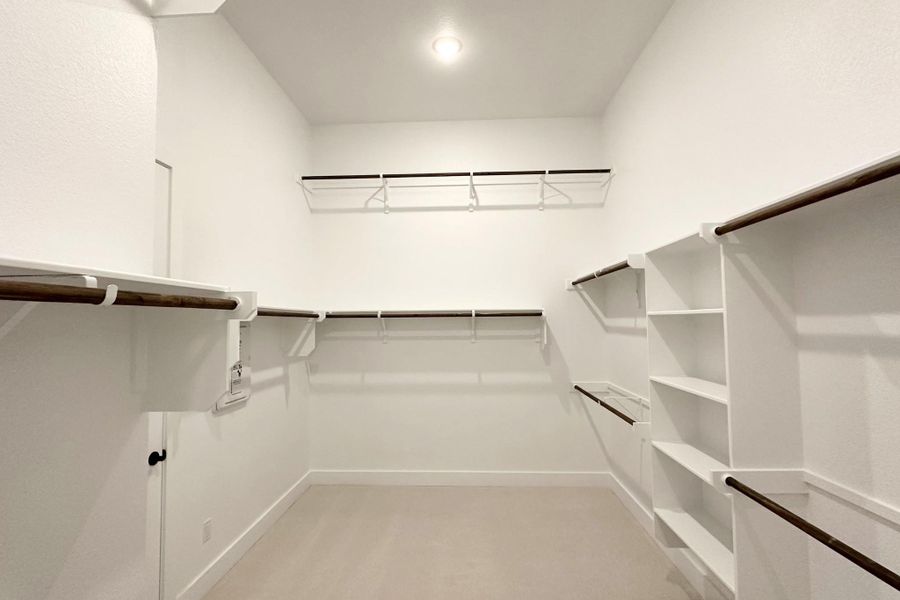 Ample shelving and hanging space in this pristine, naturally illuminated walk-in closet.