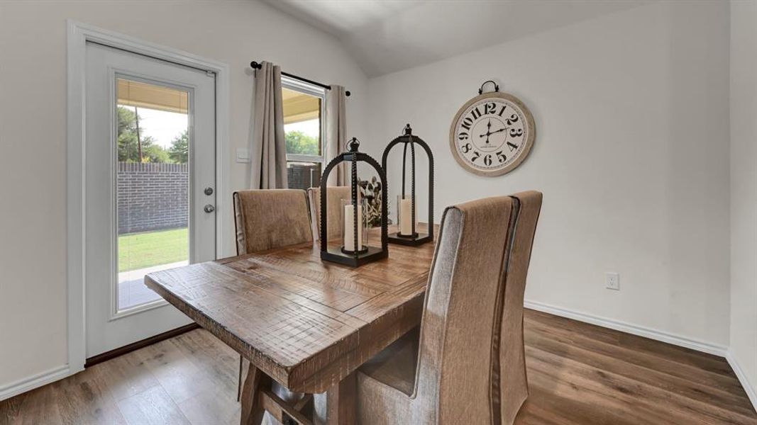 Dining room with vaulted ceiling and dark wood-type flooring