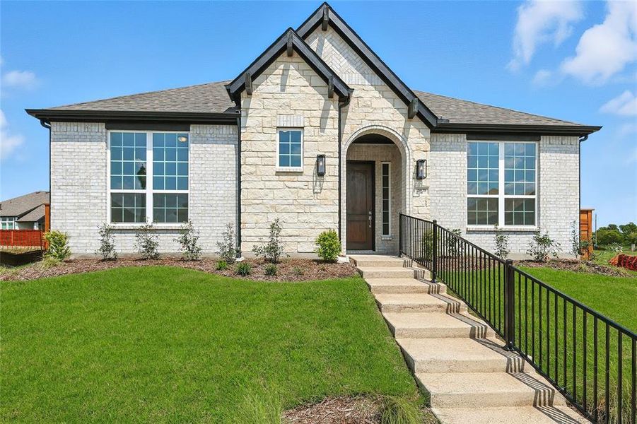 French country home featuring roof with shingles, a front yard, and brick siding