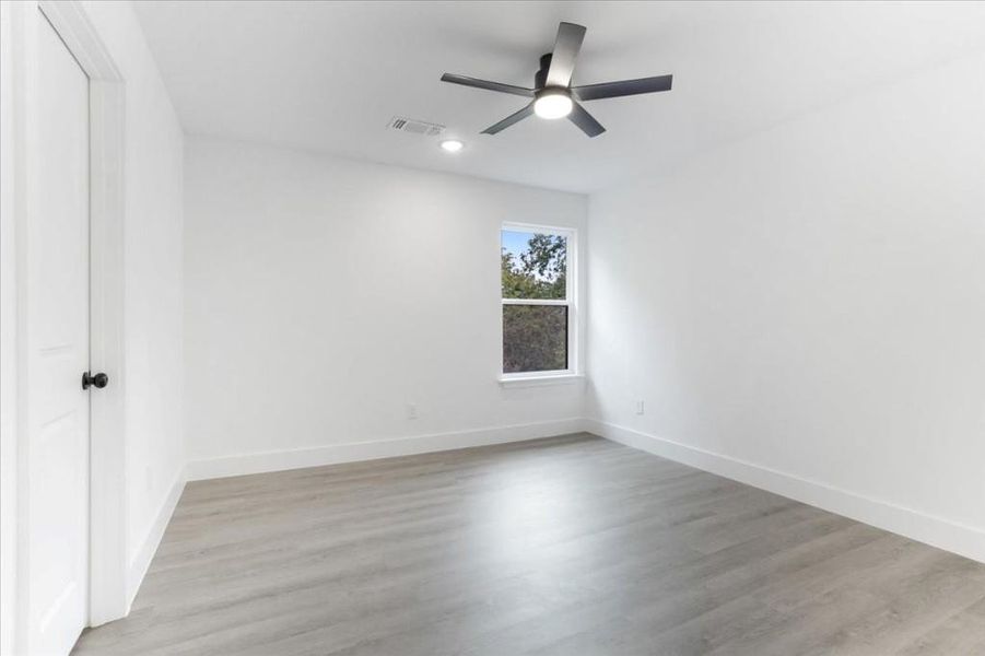 Empty room with ceiling fan and light wood-type flooring