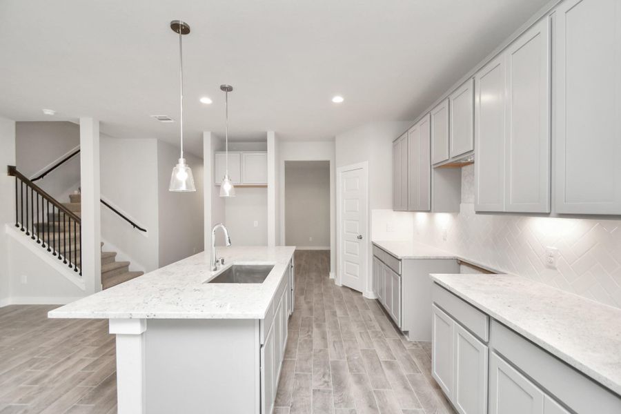 The kitchen is a culinary haven, featuring granite countertops, a tile backsplash, stainless steel appliances, 42” upper cabinets, and undercabinet lighting. Sample photo of completed home with similar floor plan. As-built interior colors and selections may vary. The kitchen is a culinary haven, featuring granite countertops, a tile backsplash, stainless steel appliances, 42” upper cabinets, and undercabinet lighting. Sample photo of completed home with similar floor plan. As-built interior colors and selections may vary.