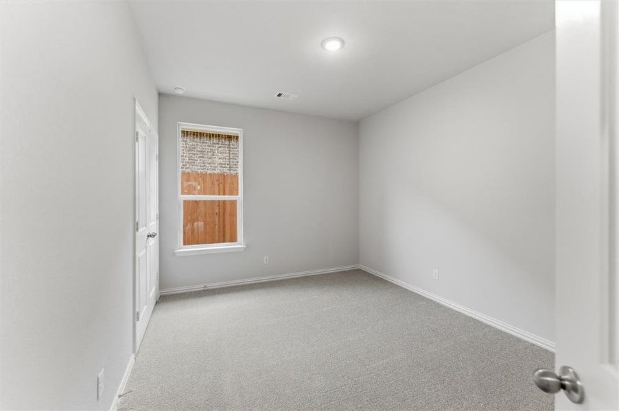 Neutral gray carpeted room featuring a white-trimmed window, a white paneled door, and recessed lighting