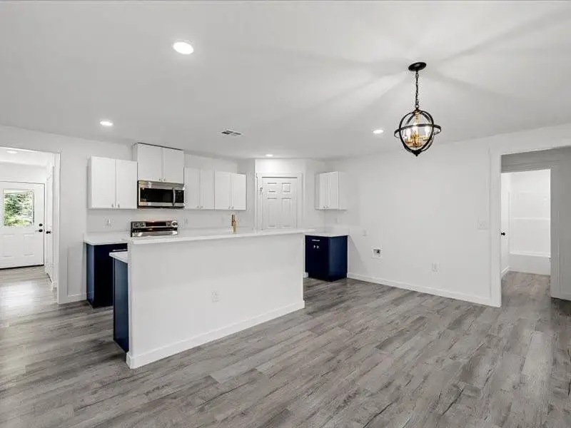 Kitchen with white cabinets, a kitchen island, light countertops, decorative light fixtures, and recessed lighting