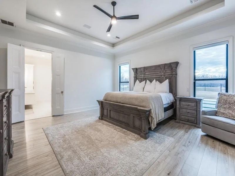 Bedroom featuring a tray ceiling, light wood-style flooring, ceiling fan, and recessed lighting