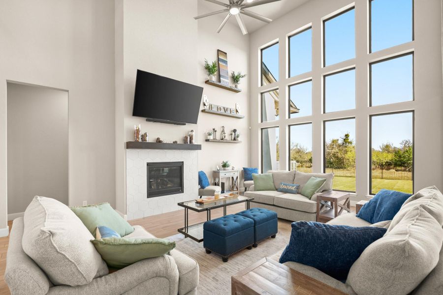 Living area featuring a glass covered fireplace, wood finished floors, plenty of natural light, and a towering ceiling Living area featuring a glass covered fireplace, wood finished floors, plenty of natural light, and a towering ceiling