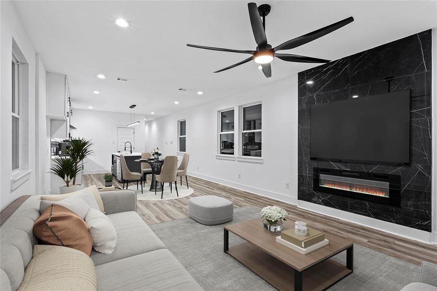 Living room with ceiling fan, light hardwood / wood-style floors, and a high end fireplace