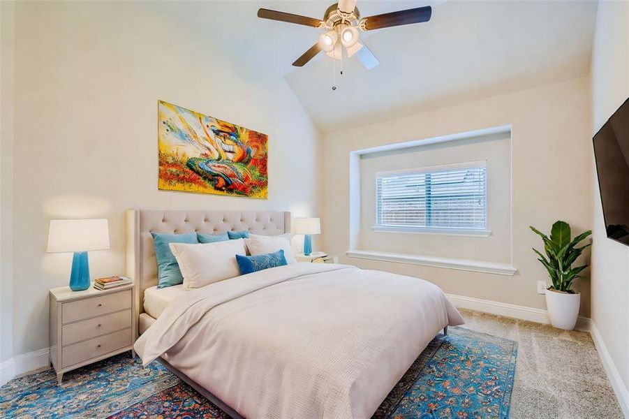 Bedroom with ceiling fan, light carpet, and lofted ceiling