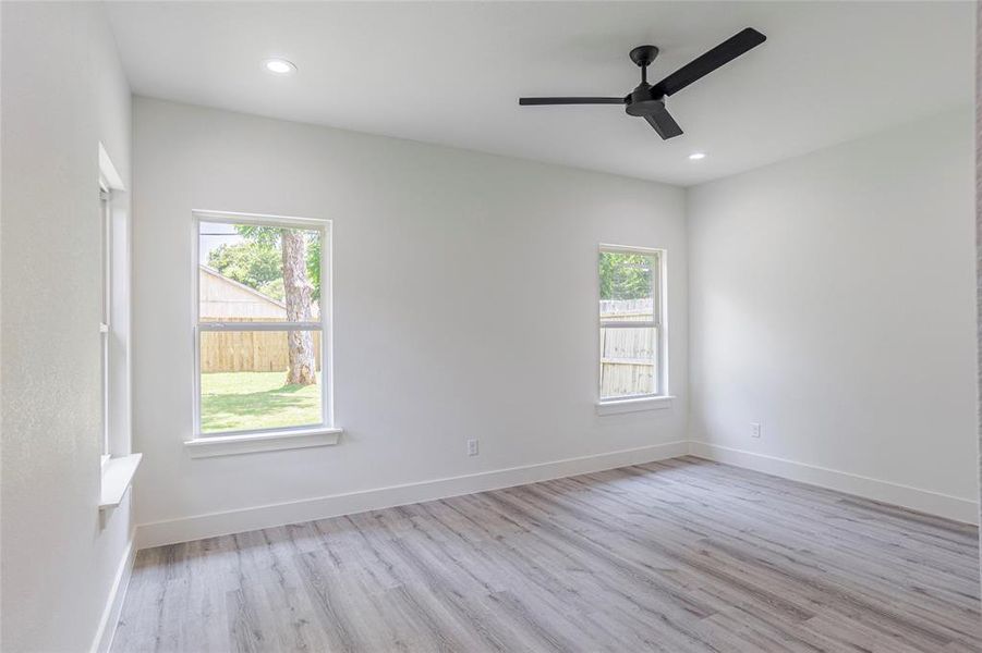 Empty room featuring light hardwood / wood-style flooring, a healthy amount of sunlight, and ceiling fan