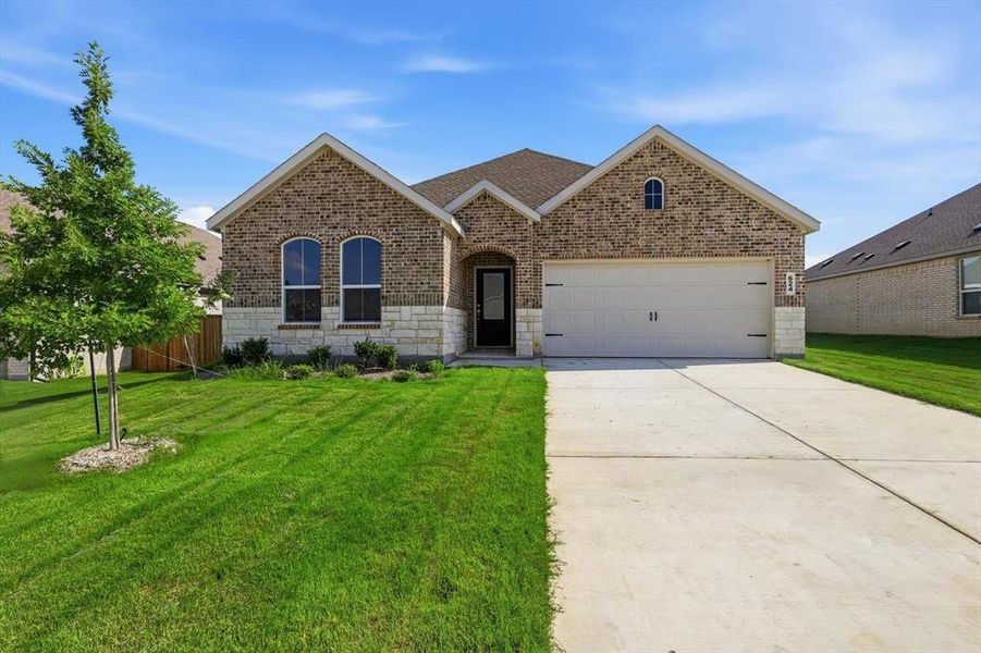 Brick and stone facade featuring a two-car garage, arched windows, and a concrete driveway Brick and stone facade featuring a two-car garage, arched windows, and a concrete driveway