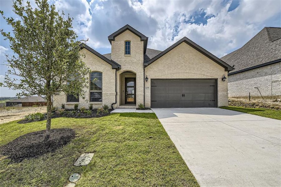 French country home with a front yard and a garage