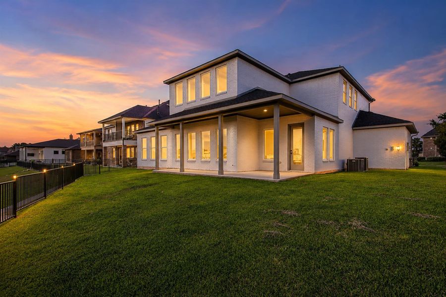 Twilight rear exterior showcasing the covered patio and large backyard