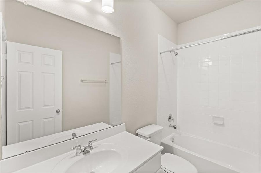 The secondary bath features tile flooring, white cabinetry and light countertops and a shower/tub combo. Perfect for accommodating any visiting family and friends.