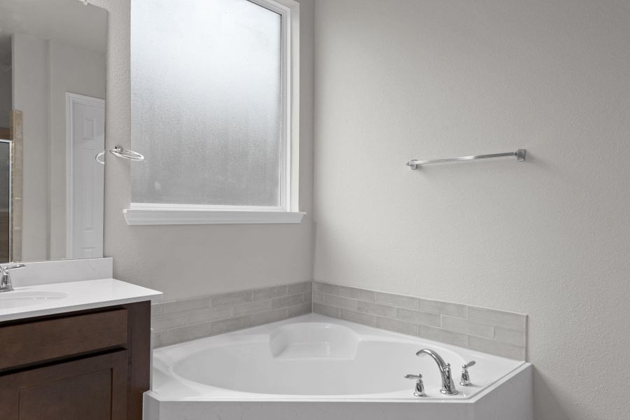 This additional view of your primary bathroom features tile flooring, fresh paint, walk-in shower, a separate garden tub, and a large walk-in closet.