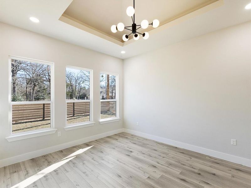 Spare room featuring recessed lighting, a chandelier, light wood-style flooring, and a raised ceiling