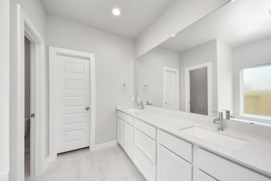 Elevate your daily routine at the elegant vanity, now equipped with double sinks, light countertops, modern hardware, and beautiful recessed lights.