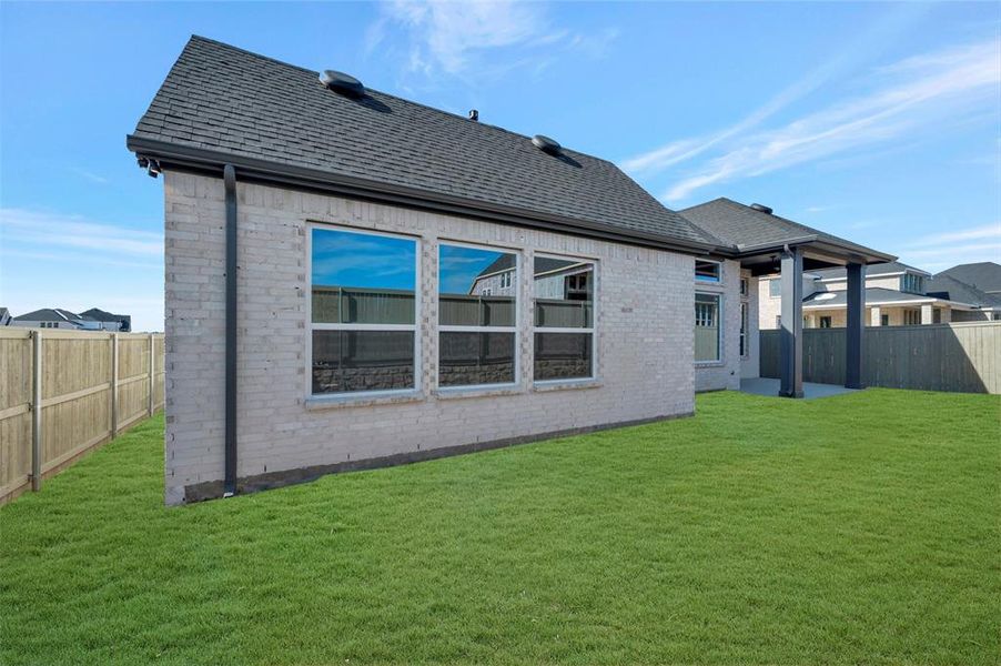 Back of house featuring a fenced backyard, a patio area, brick siding, and a shingled roof
