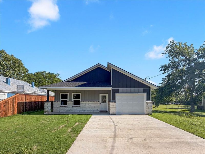 Contemporary single-story residence featuring a stone veneer facade, horizontal siding, and a striking dark blue gable accent Contemporary single-story residence featuring a stone veneer facade, horizontal siding, and a striking dark blue gable accent