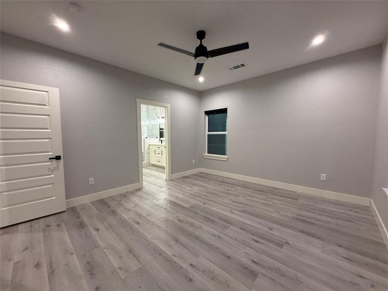 Unfurnished bedroom featuring ceiling fan, light wood-style floors, ensuite bathroom, and recessed lighting