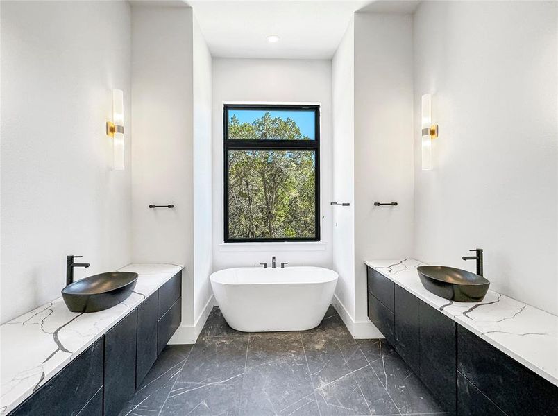 In the final stages of construction, this primary bathroom is taking shape beautifully. Featuring expansive tiles, lofty 12' ceilings, dual vanities, and a separate soaking tub, it's destined to be a luxurious retreat.