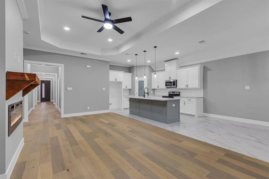 Kitchen with stainless steel appliances, sink, pendant lighting, white cabinets, and an island with sink