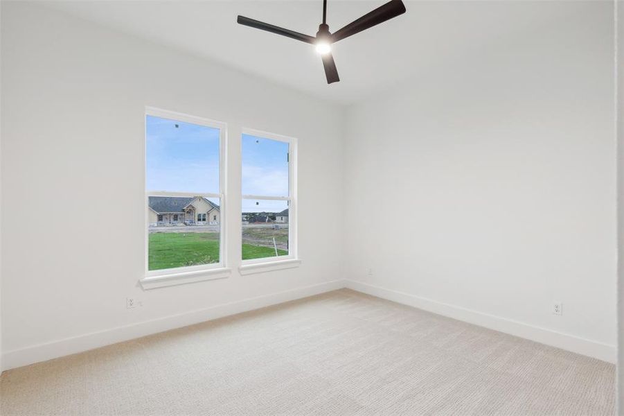 Empty room featuring ceiling fan and light carpet