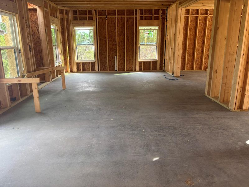 Interior view of the property under construction, featuring exposed wooden wall framing, a concrete floor, and windows providing natural light