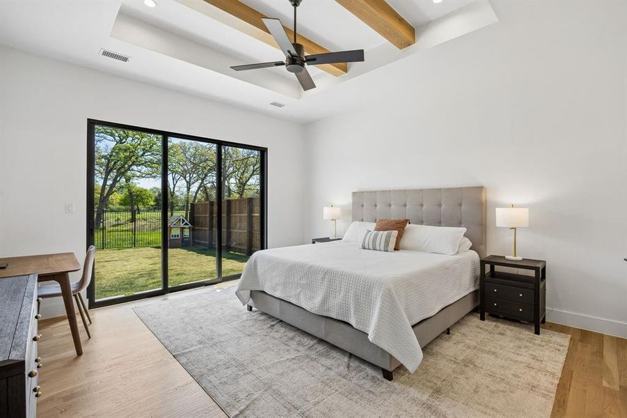 Primary Bedroom features hardwood floors, elegant sliding doors, and a beautifully detailed beamed ceiling, creating a space that is both comfortable and stylish.