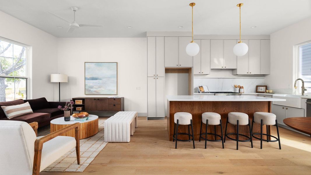Kitchen with white cabinetry, a kitchen island, light wood-style flooring, and a kitchen bar