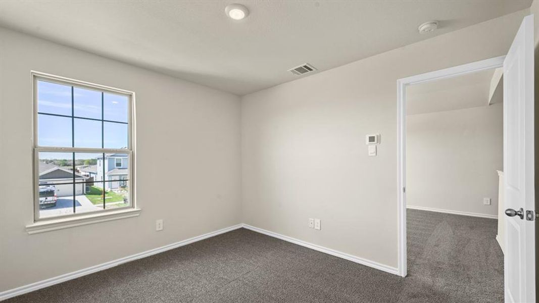 Neutral-toned room featuring a single window with grids, light grey walls, and dark grey carpet flooring